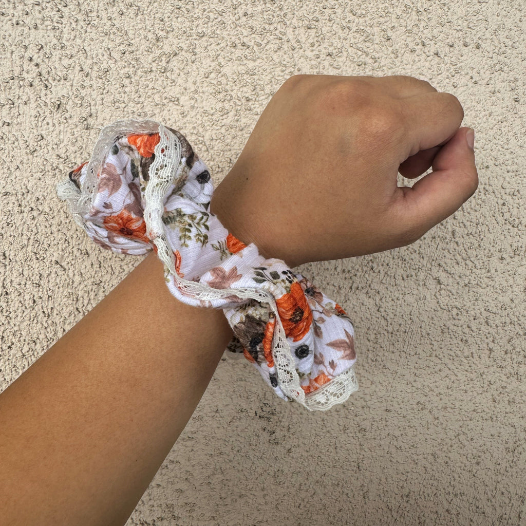 Hand wearing a floral scrunchie on a beige background