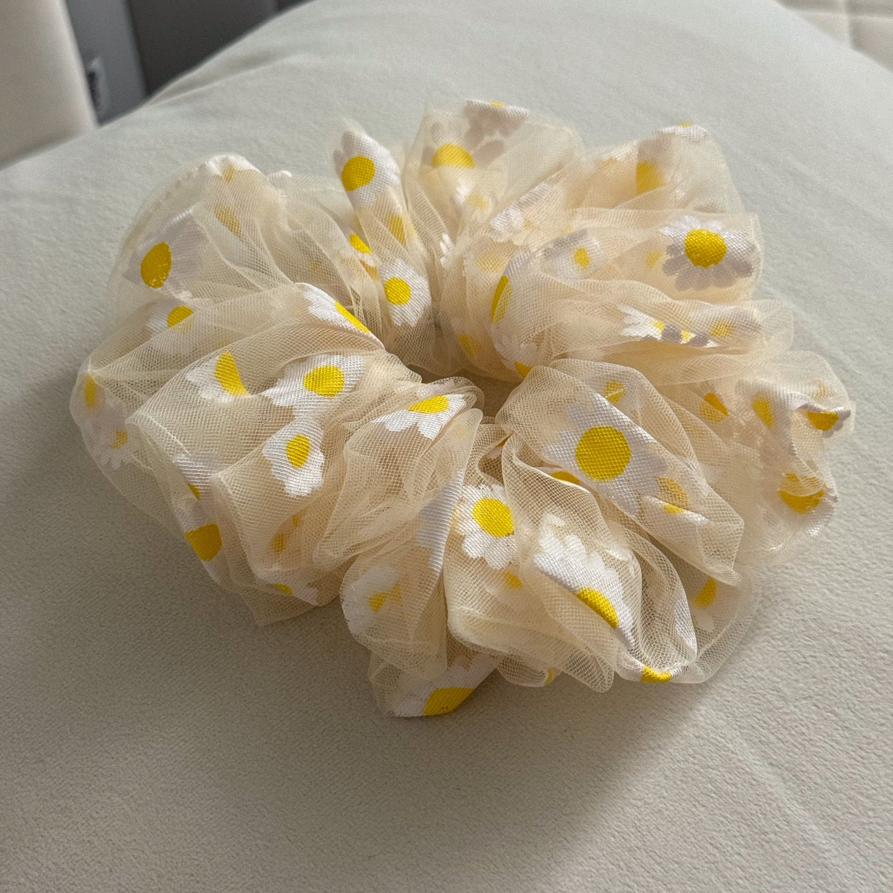 yellow scrunchie with yellow floral patterns on a light gray surface