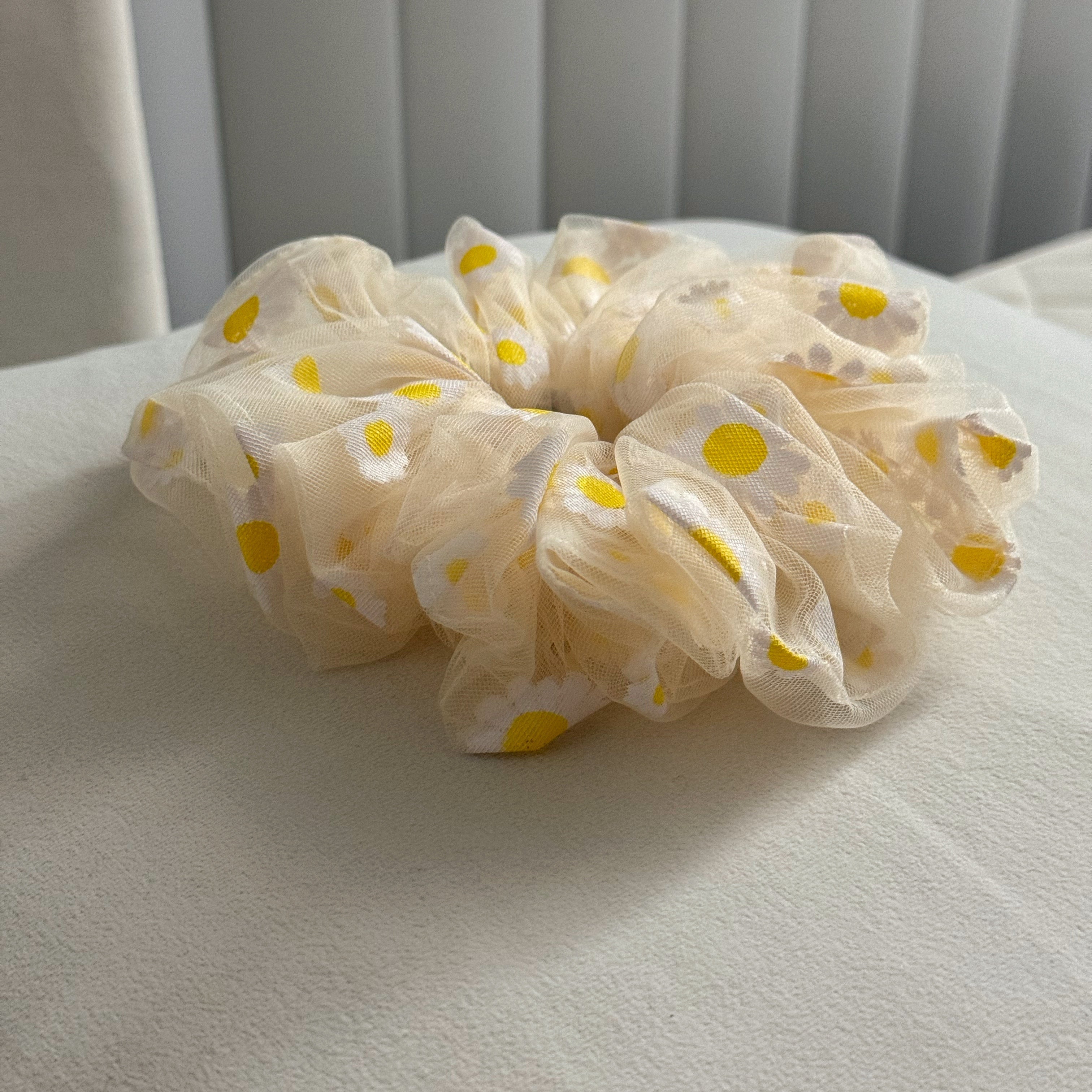 Beige scrunchie with yellow florals on a white surface