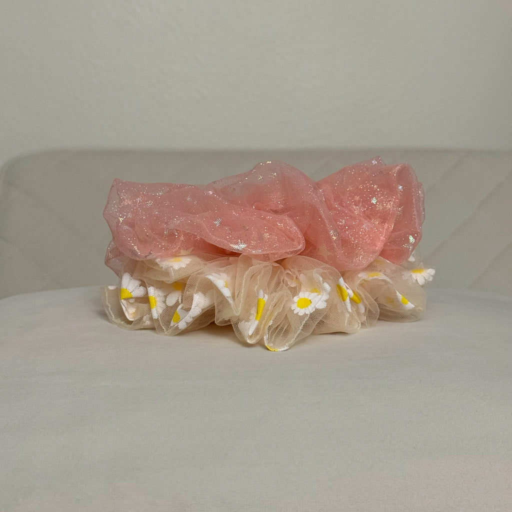 Pink and yellow hair scrunchies with floral design on a white surface