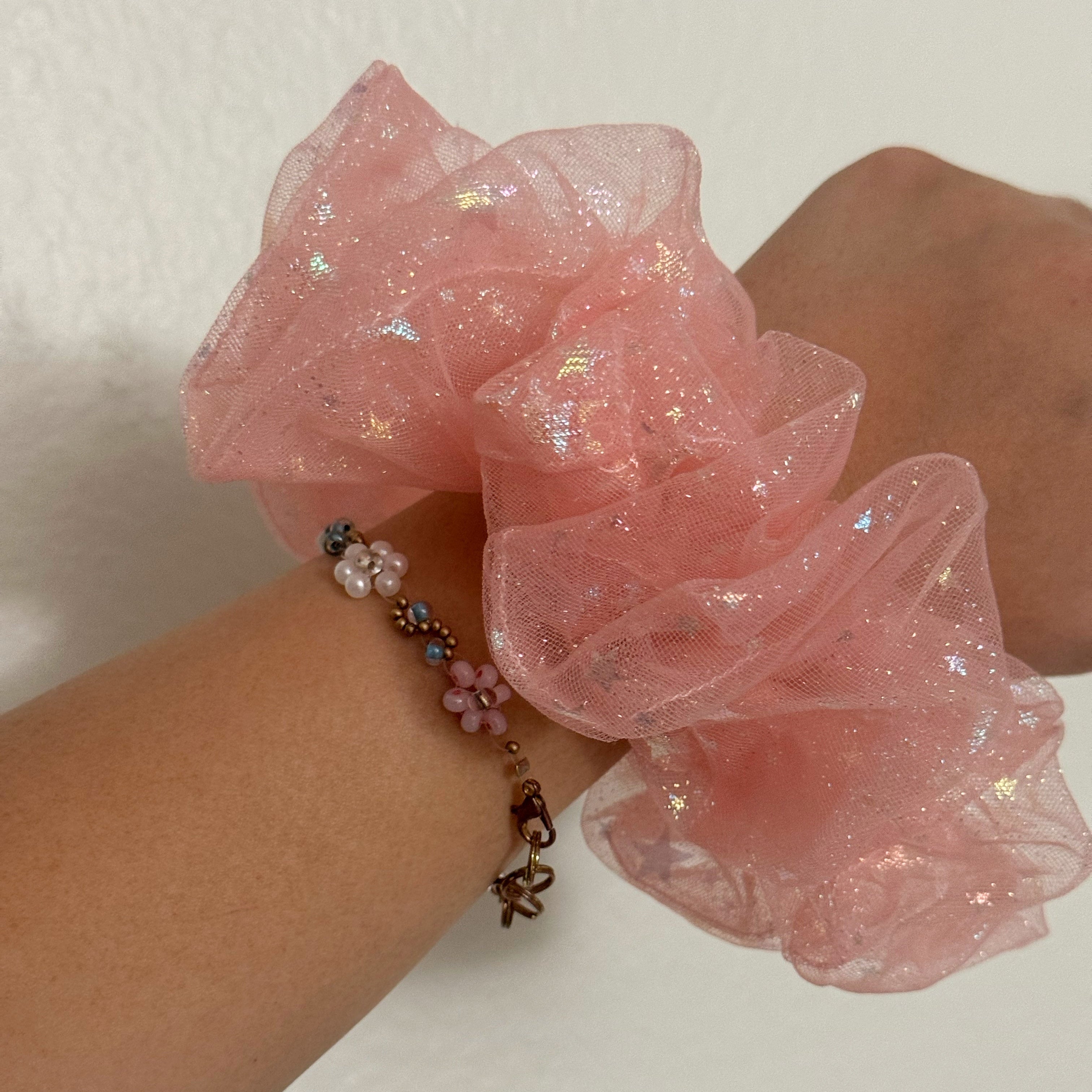 Pink scrunchie on a wrist with a white background