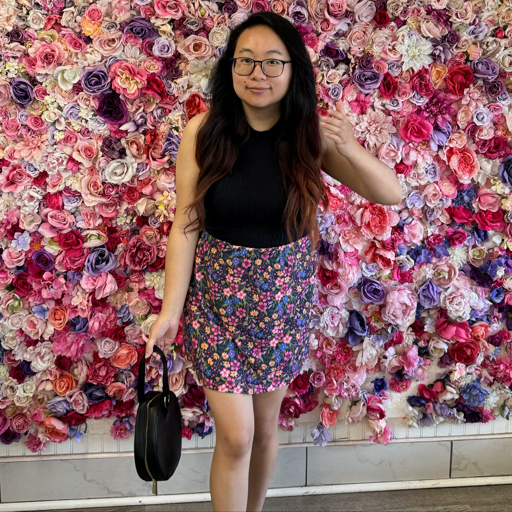Model posing in front of a vibrant floral wall wearing our Mila Skirt