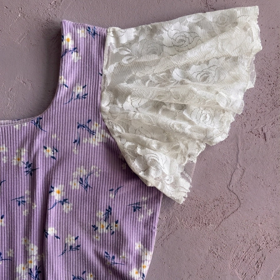 Purple dress with floral pattern and white lace trim on a textured gray background