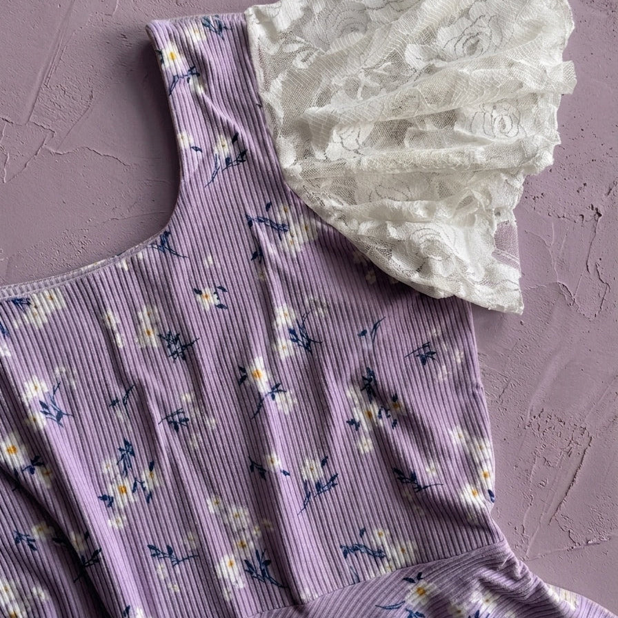 Purple floral dress with white lace trim on a textured pink background