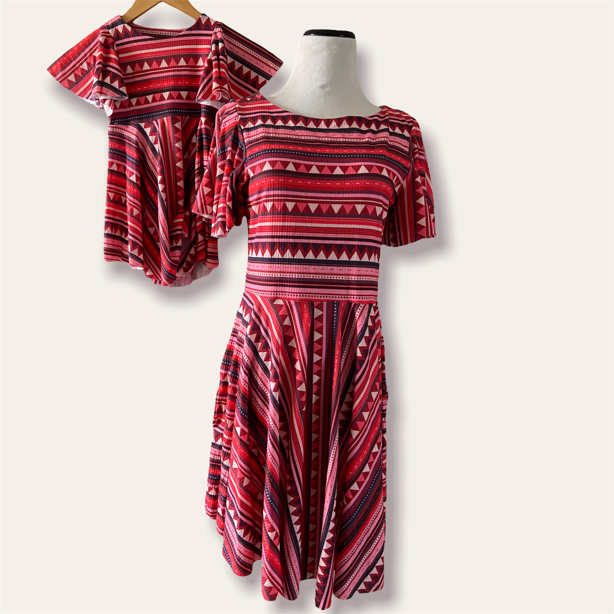Red and black patterned dress on a mannequin against a white background