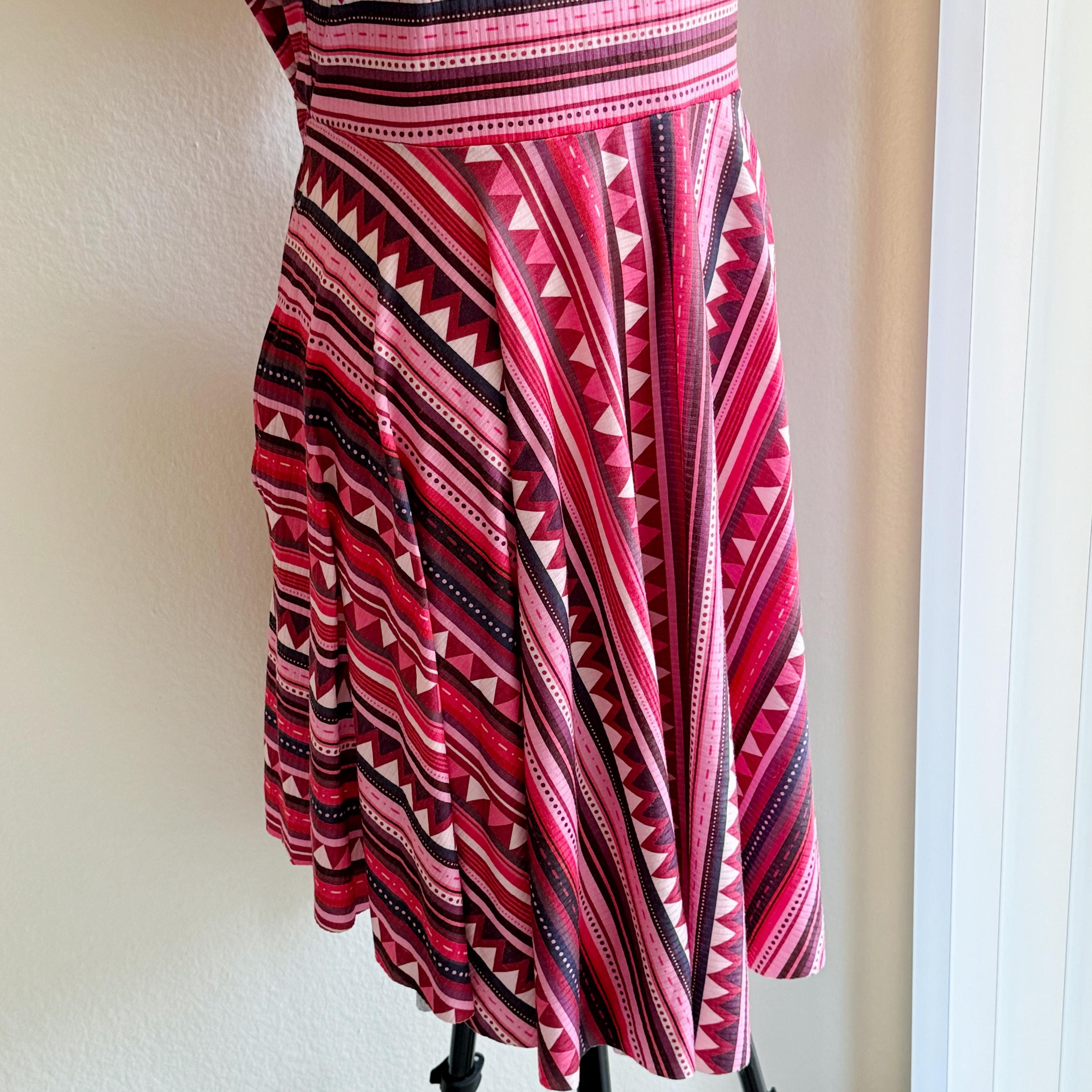 Red and black patterned dress on a mannequin against a white wall.