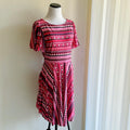 Red and black patterned dress on a mannequin against a neutral wall.