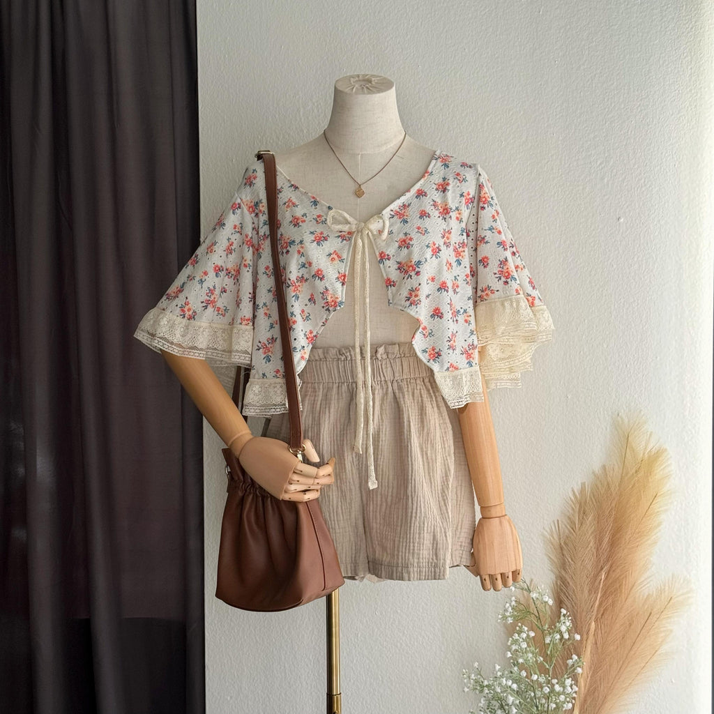 Mannequin wearing a floral top and shorts with a brown bag against a neutral background