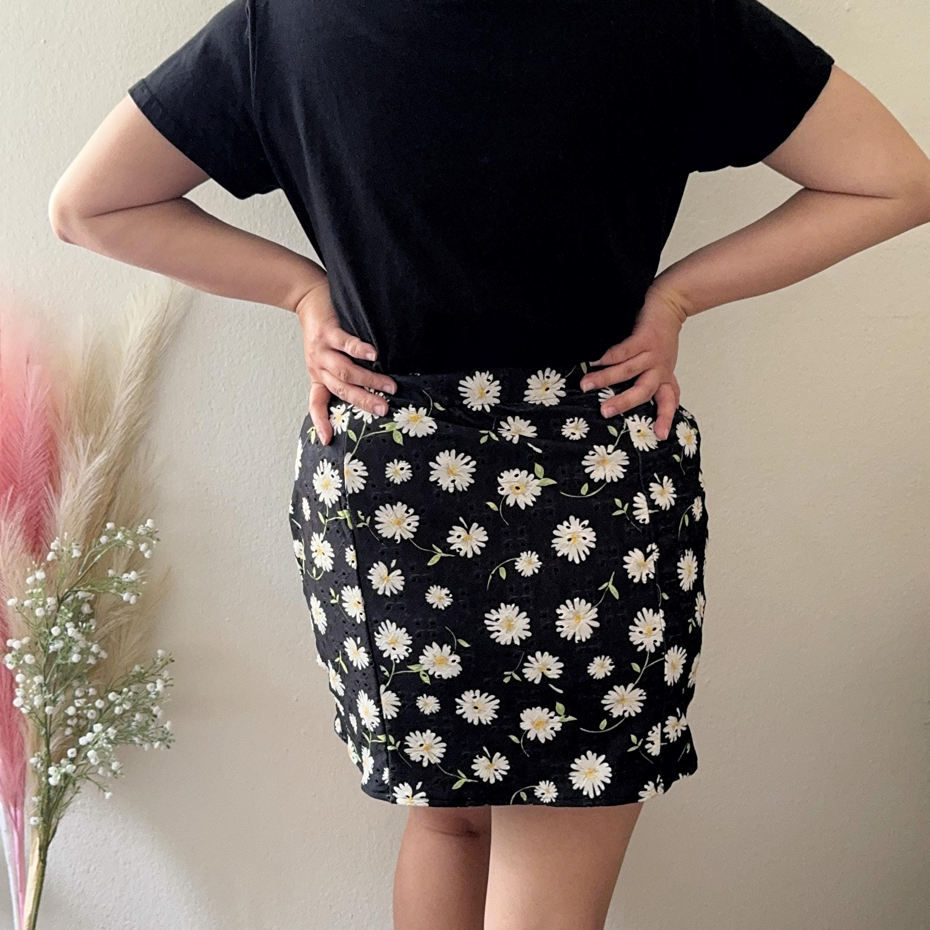 Person wearing a black floral skirt with a plain background