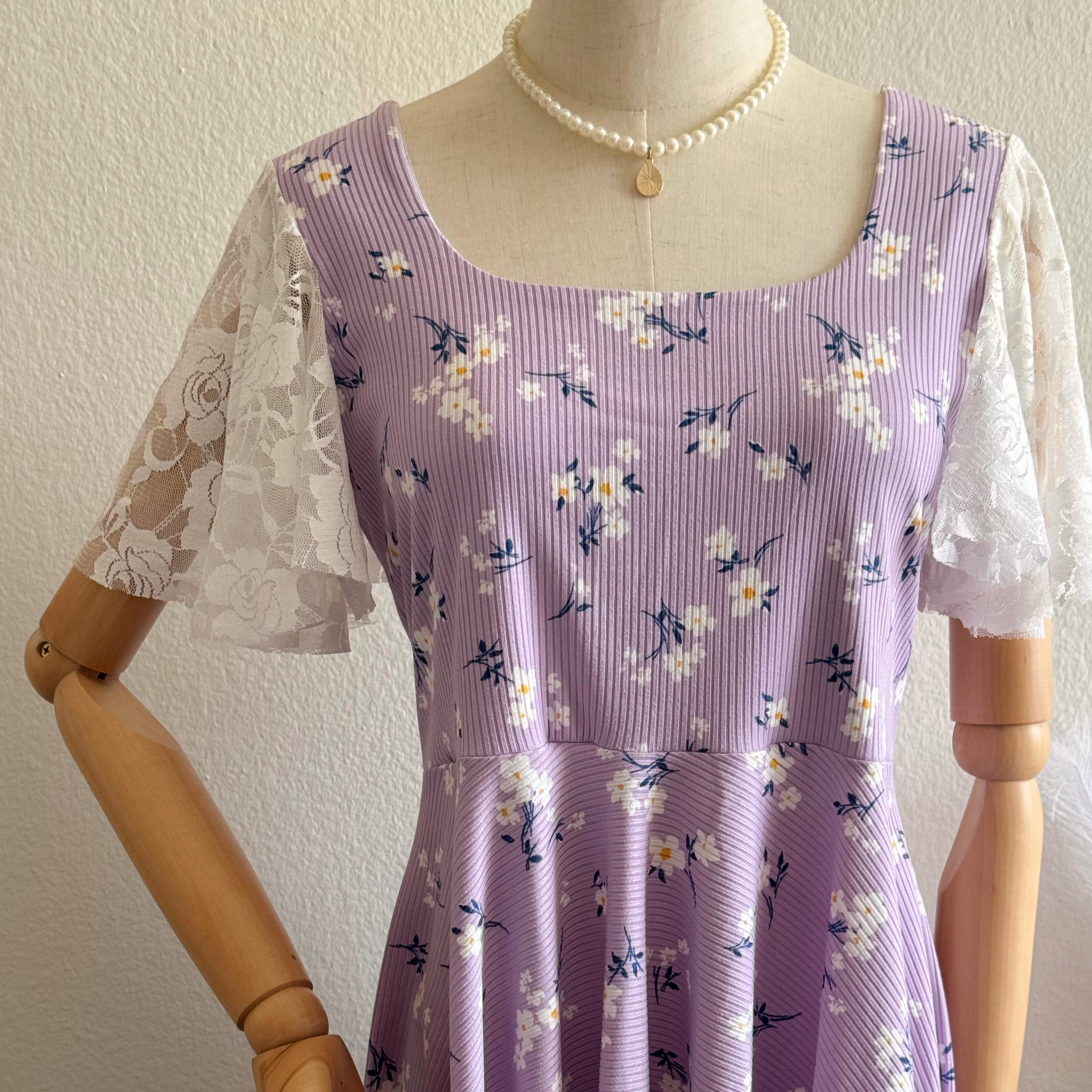 Purple floral dress with white lace sleeves on a mannequin against a plain background