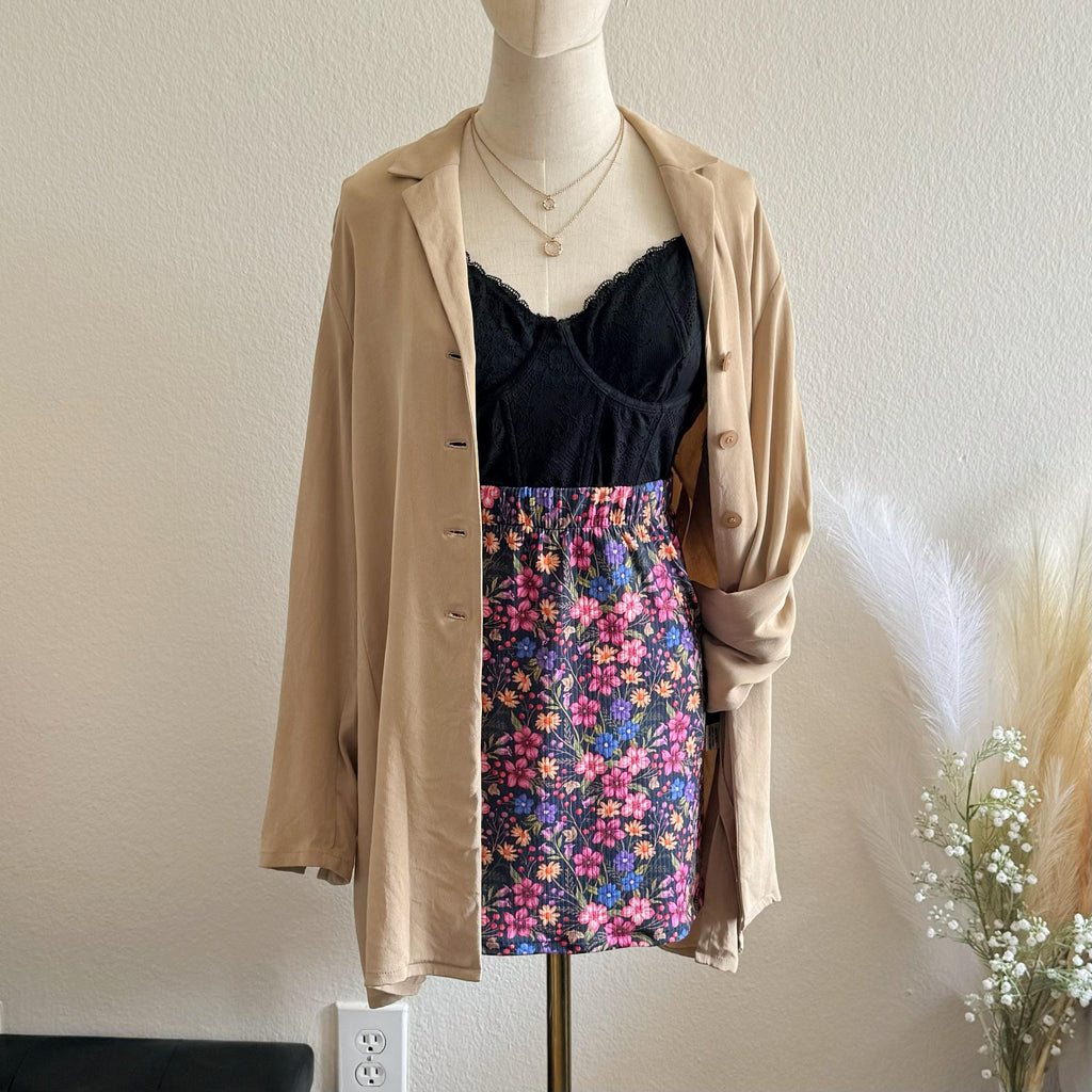 Mannequin wearing a beige cardigan over a floral skirt and black top with a plain background