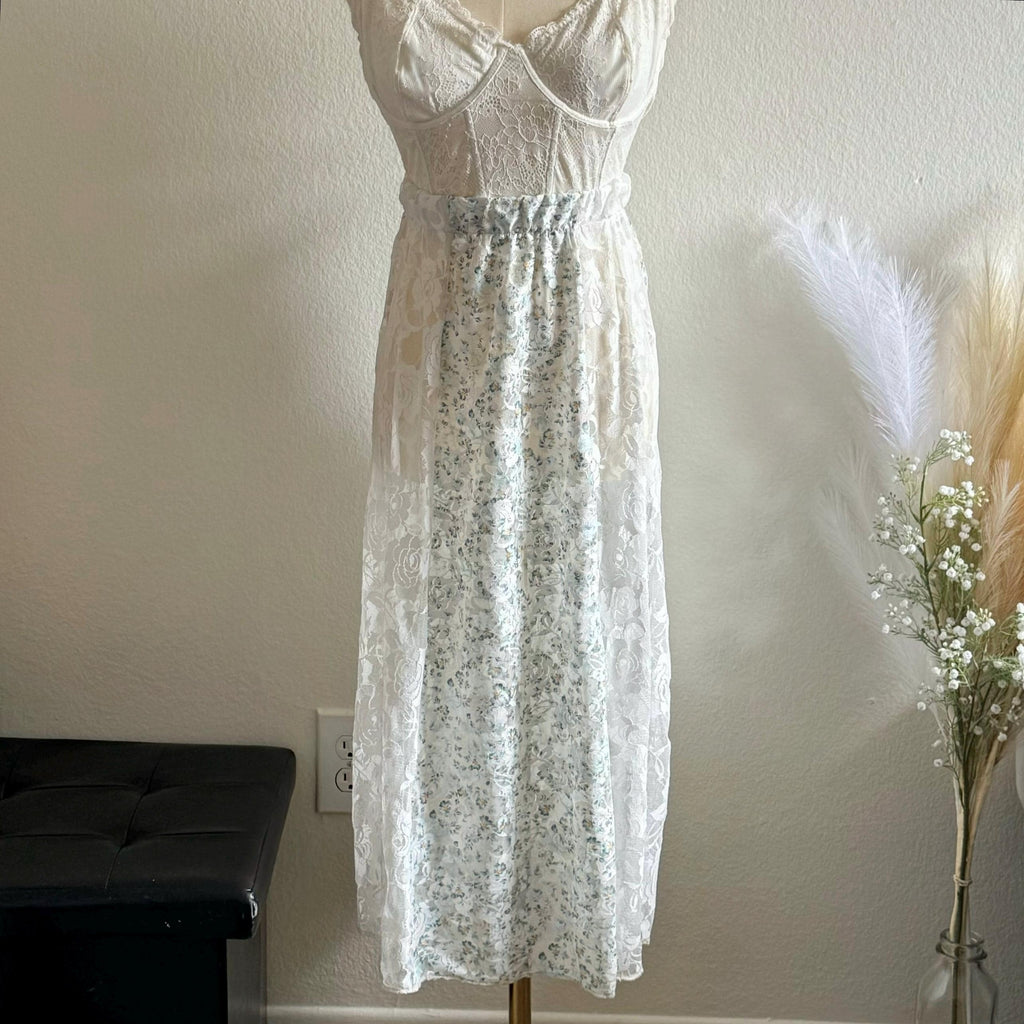 White lace dress on a mannequin against a plain wall with decorative elements.