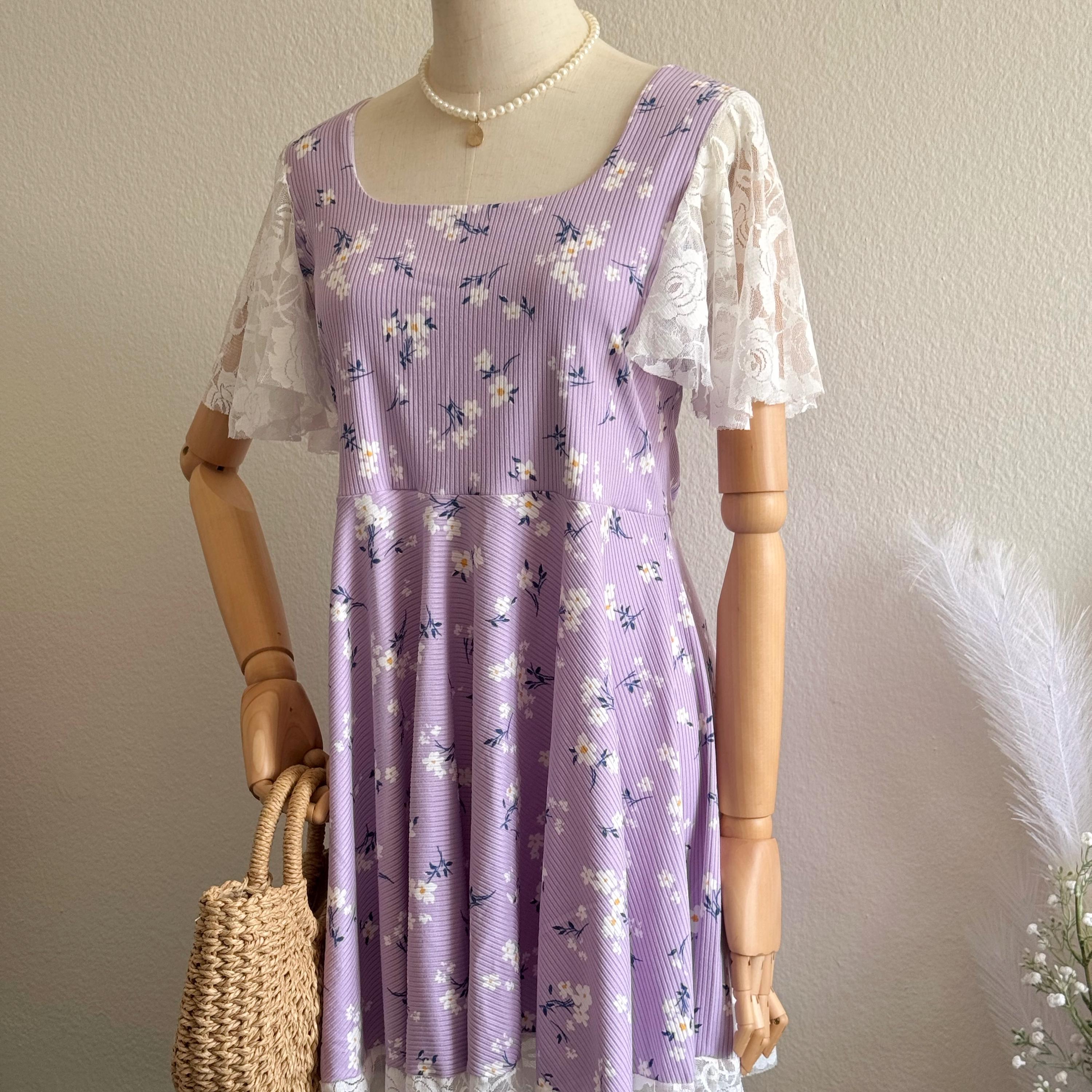Mannequin wearing a purple floral dress with lace sleeves against a plain background