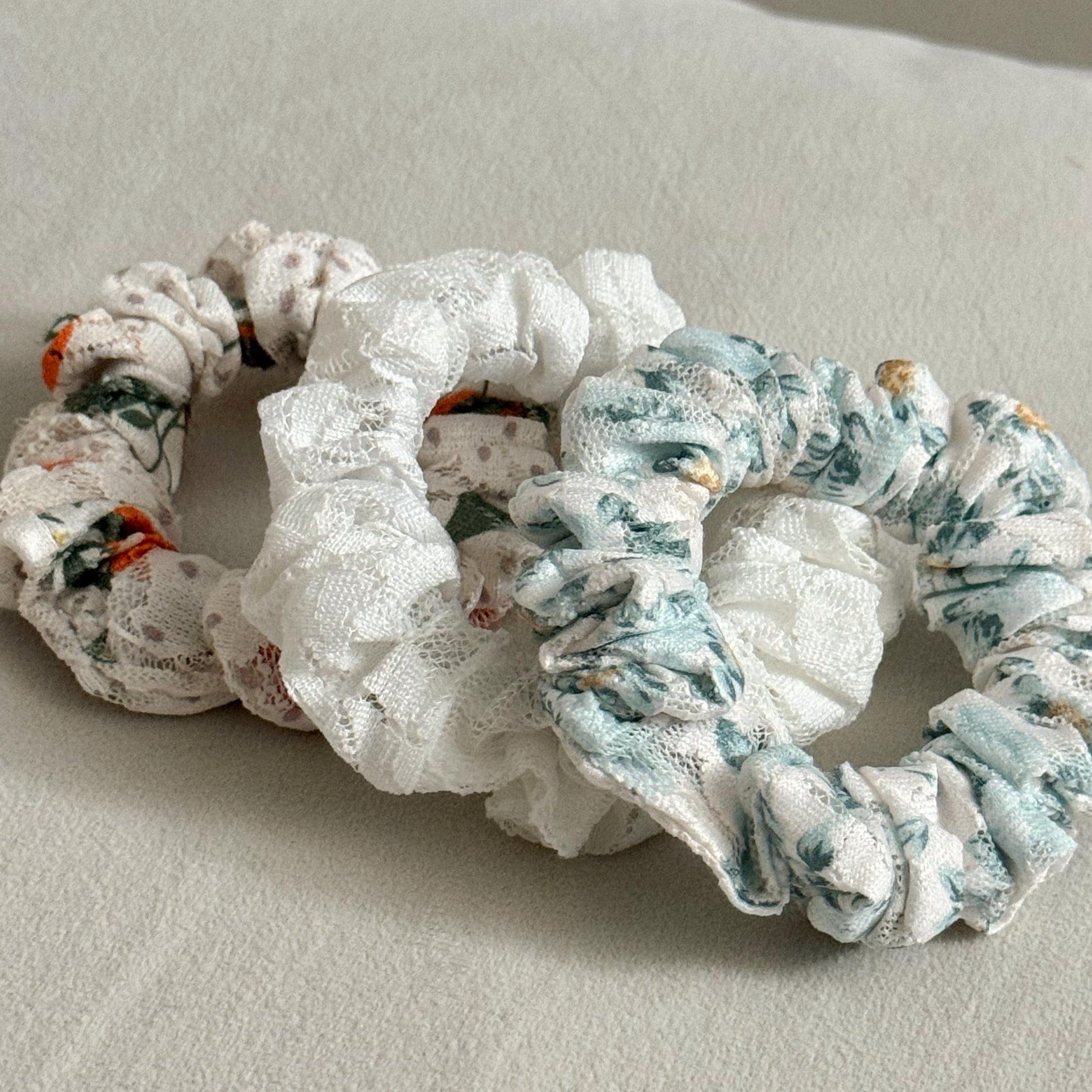 Three floral-patterned scrunchies on a light gray surface