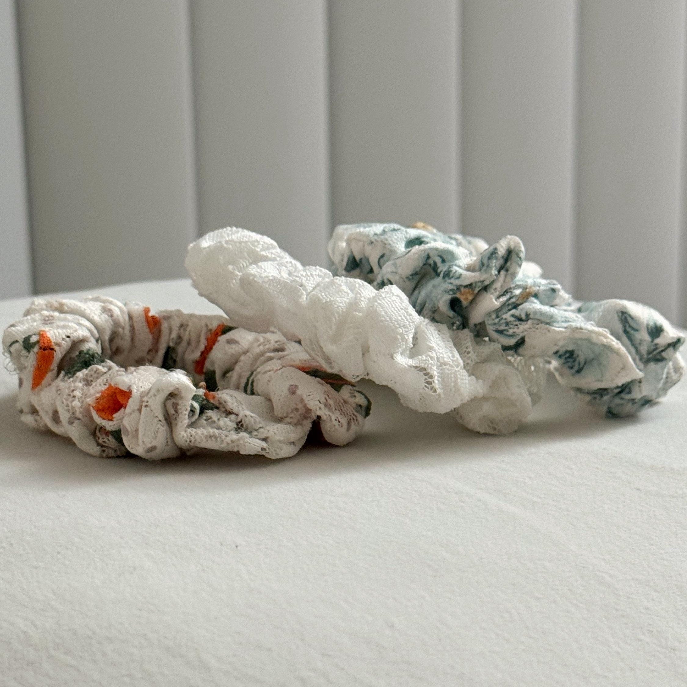 Two fabric scrunchies on a textured surface with a neutral background