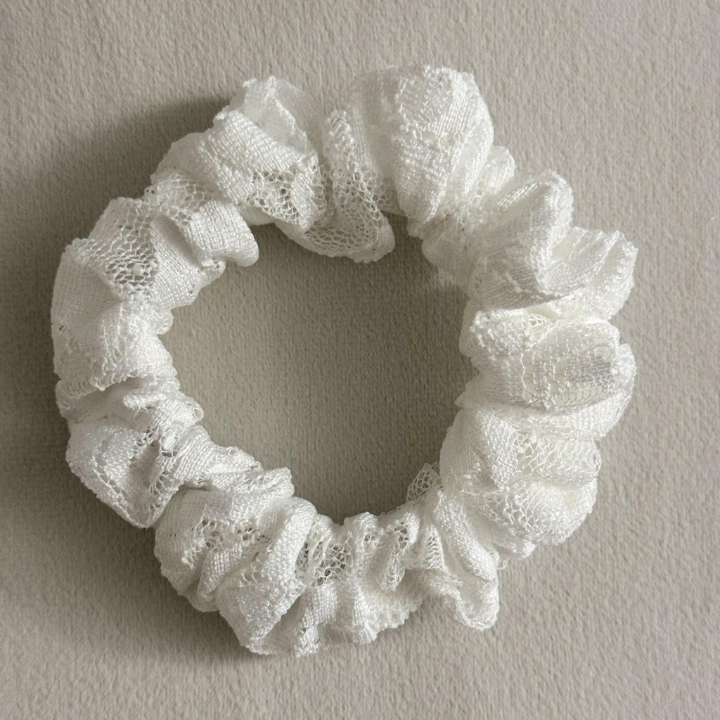 White lace scrunchie on a plain background
